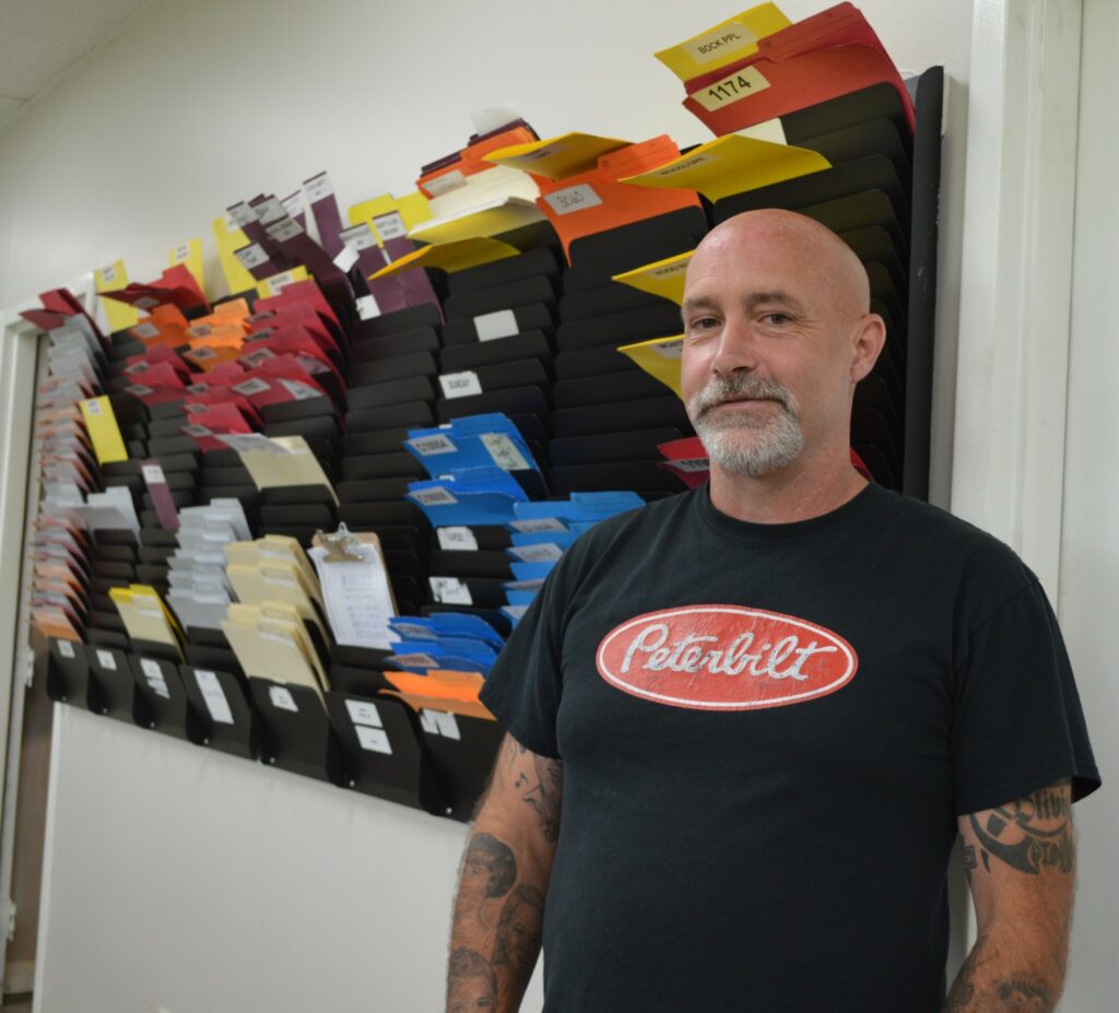  Devon Turnbull, dispatch manager at Sharp Transportation in Cambridge, Ont. is old school and likes to have all the paperwork on a wall with folders, where orders and driver names are inserted. (Photo: Leo Barros) 