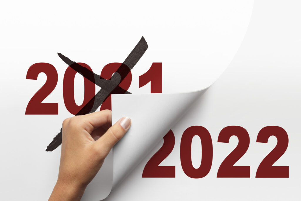 A woman turns the page from 2021 to 2022.  An "X" has been drawn across 2021 indicating good riddance to a difficult year.