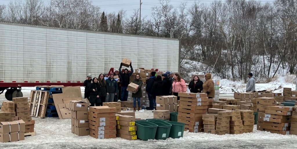 Picture of people with donated food in boxes near a trailer