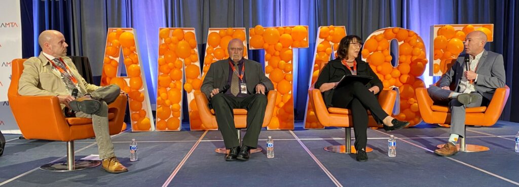 People seated on chairs on stage at AMTA's conference
