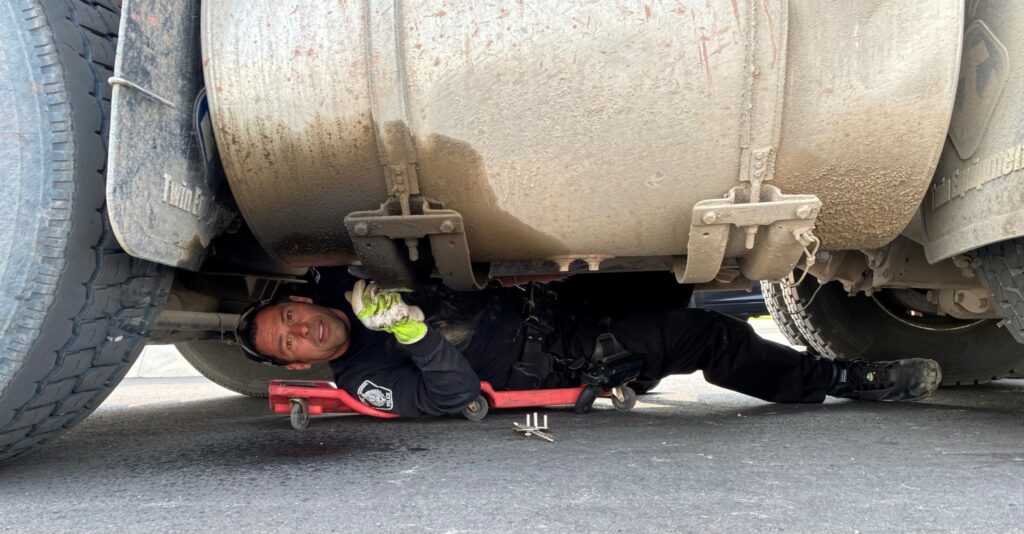 Picture of a leaking fuel tank and officer under truck