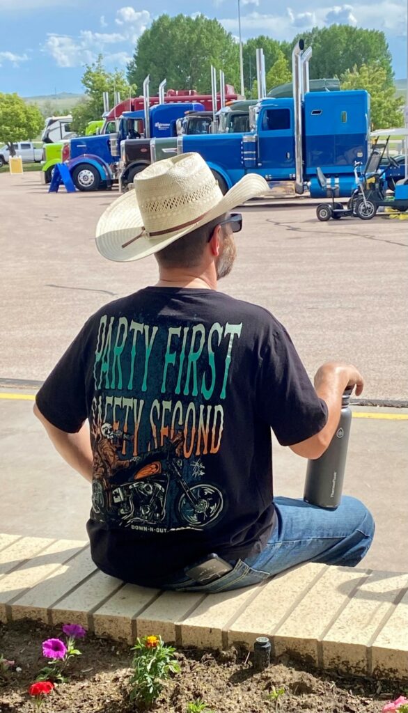 Cowboy sitting near parked trucks