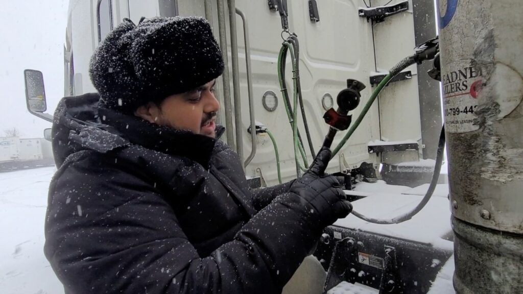 Man connecting air lines to the trailer in the snow