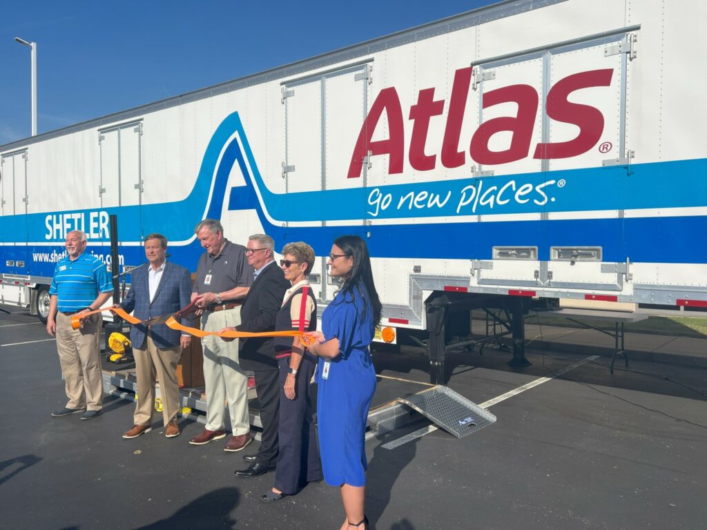 People cut a ribbon in front of a trailer