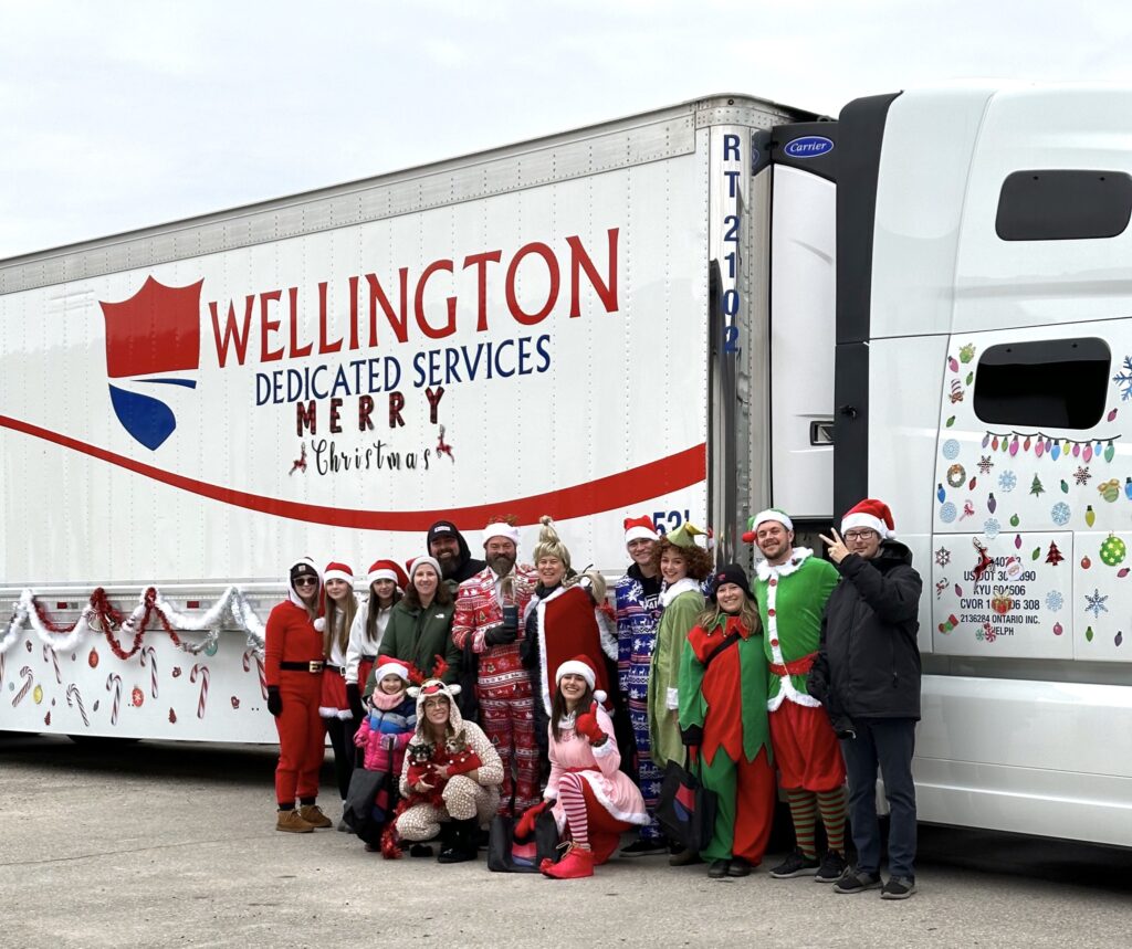 People dressed in Christmas outfits standing outside a decorated truck
